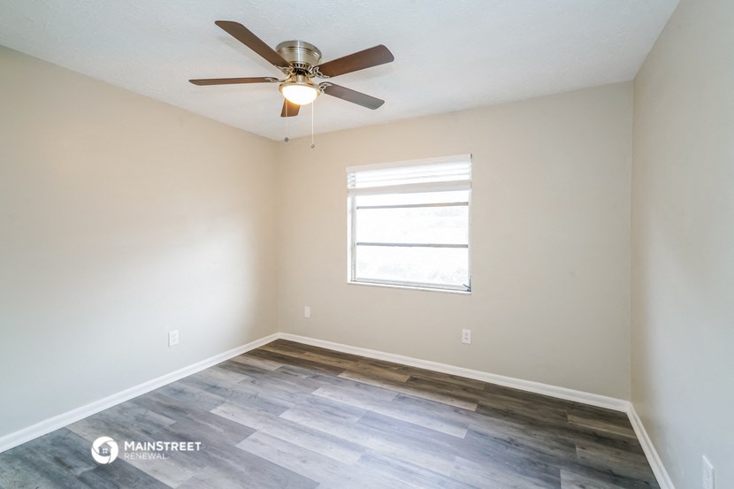 an empty room with a ceiling fan and a window