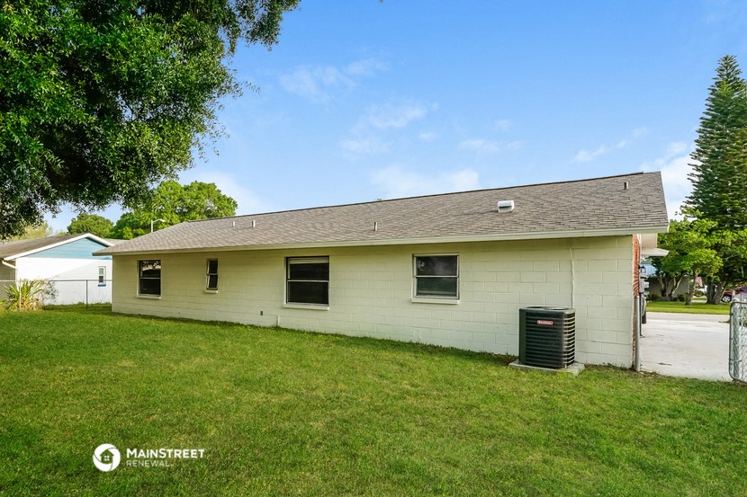 a white brick house with a yard and a trash can