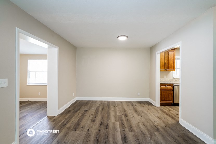 the spacious living room with wood flooring and white walls