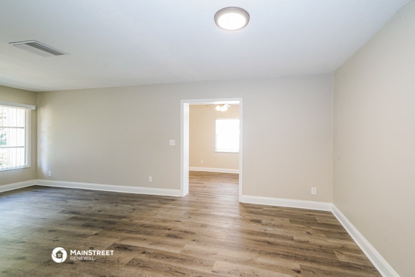 the spacious living room with wood flooring and white walls