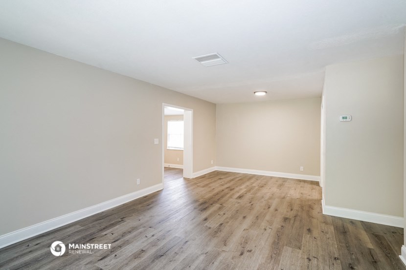 the spacious living room with wood flooring and white walls
