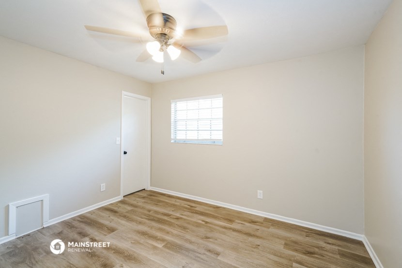 the spacious living room with ceiling fan and wood flooring