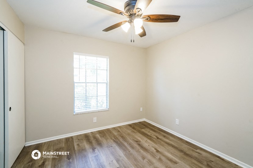 an empty room with a ceiling fan and a window