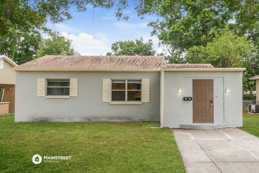 a small white house with a brown door and a lawn