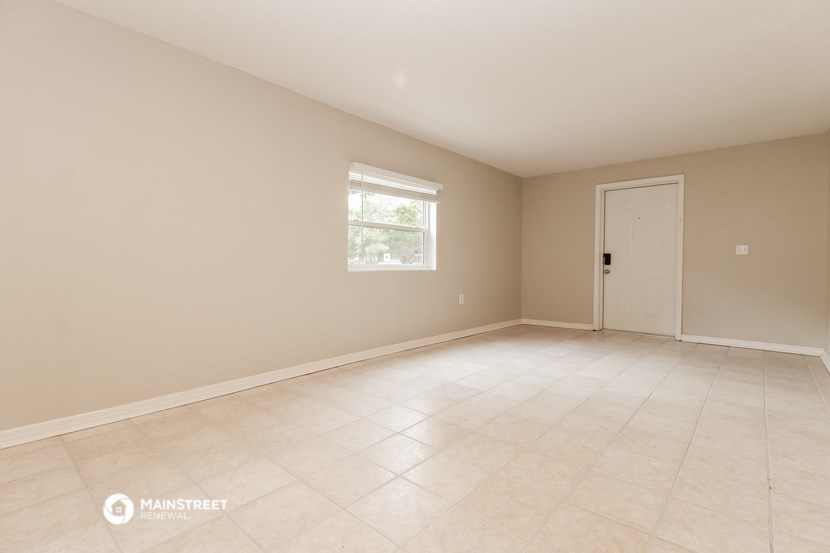 an empty living room with a white tiled floor and a window