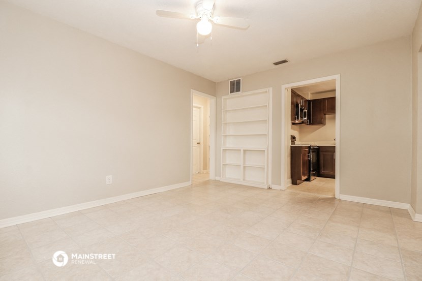 the spacious living room with tile flooring and an open door to the kitchen
