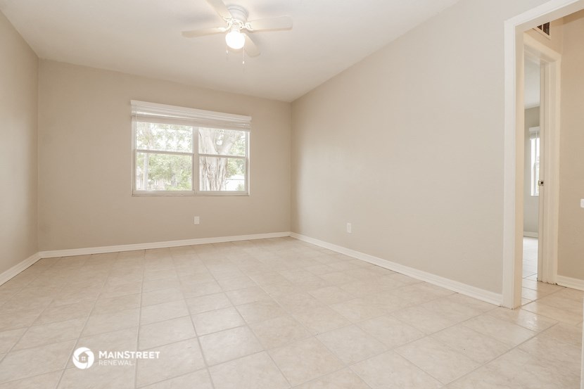 the spacious living room with tile flooring and a ceiling fan