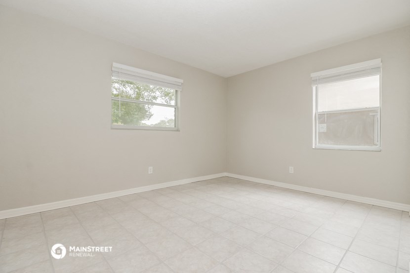 an empty room with two windows and a tiled floor