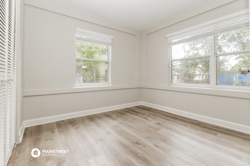 the living room of a home with wood floors and two windows