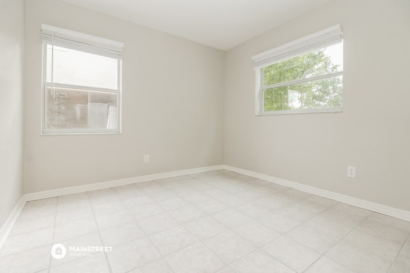 an empty room with two windows and a tiled floor
