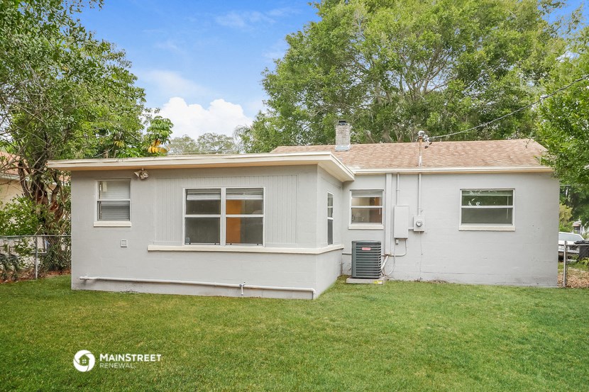 a small white house with a lawn and trees