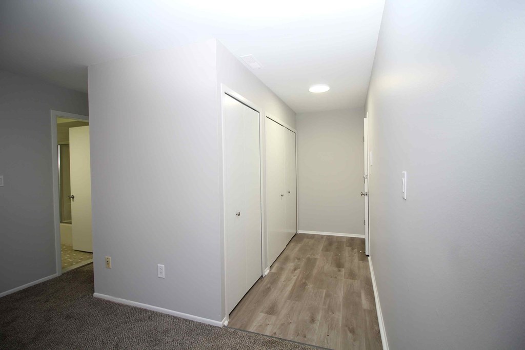 a room with white walls and wood floors and a closet