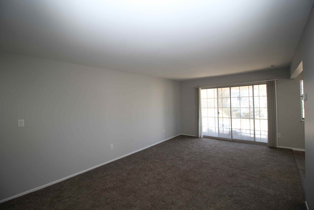 an empty living room with white walls and a sliding glass door