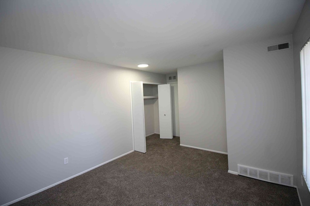 a room with white walls and carpet and a closet