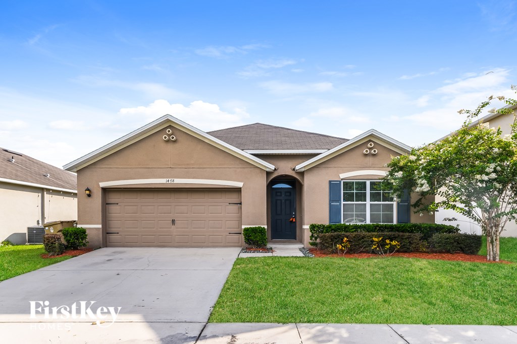 A house with a garage and a driveway in front of it.