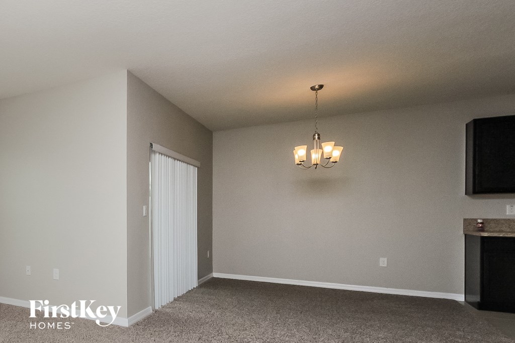 A room with a chandelier and a television on the wall.