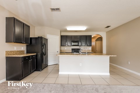 A kitchen with black cabinets and a white island.