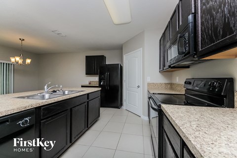 A kitchen with black cabinets and a FirstKey Homes logo.