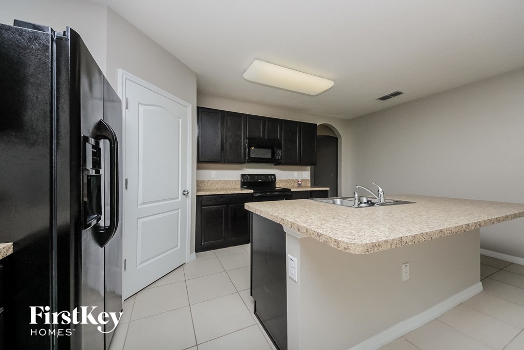 A kitchen with a black fridge and a counter top.