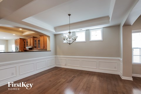 an empty dining room with white wainscoting and a chandelier