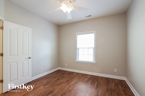 a bedroom with wood flooring and a ceiling fan