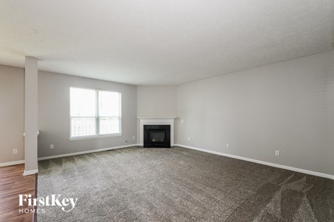 A spacious living room with a fireplace and a large window.