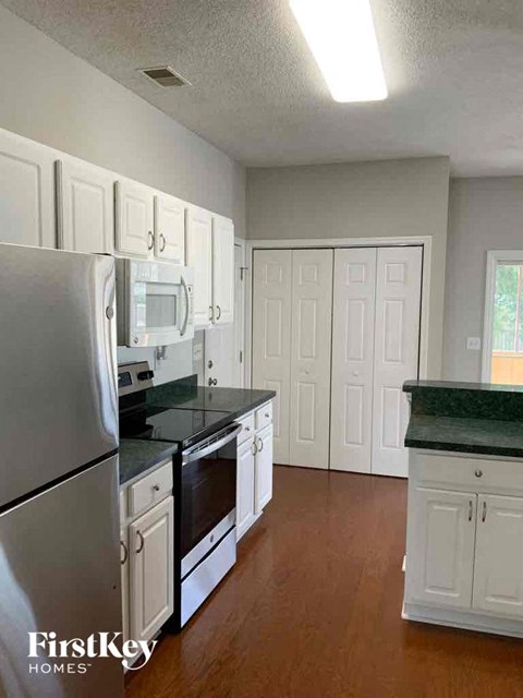 a kitchen with white cabinets and a stainless steel refrigerator