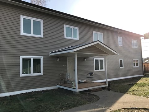 A house with a grey siding and a white porch.
