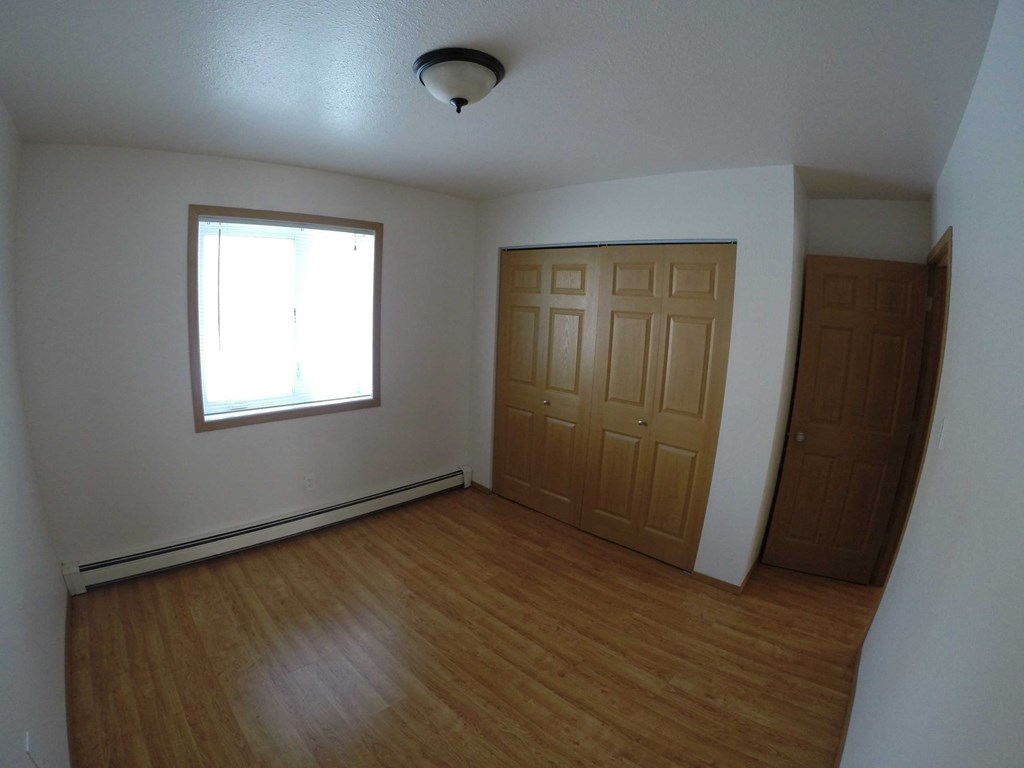 A room with a window and a wooden door.