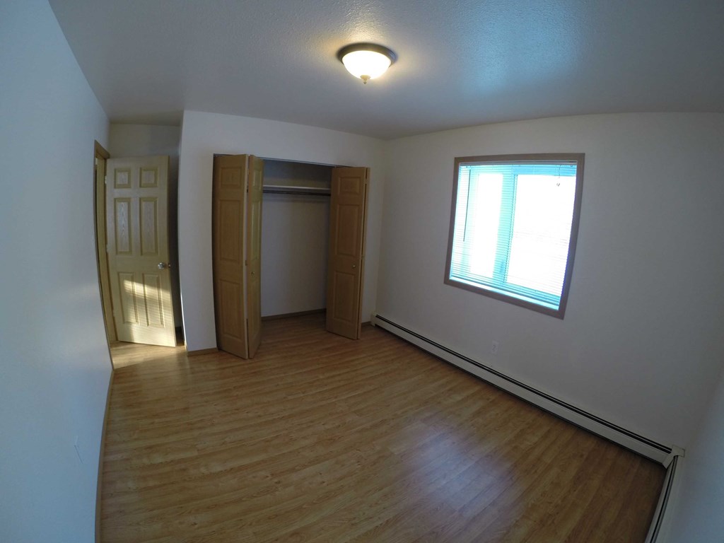 A room with wooden floors and a window letting in sunlight.