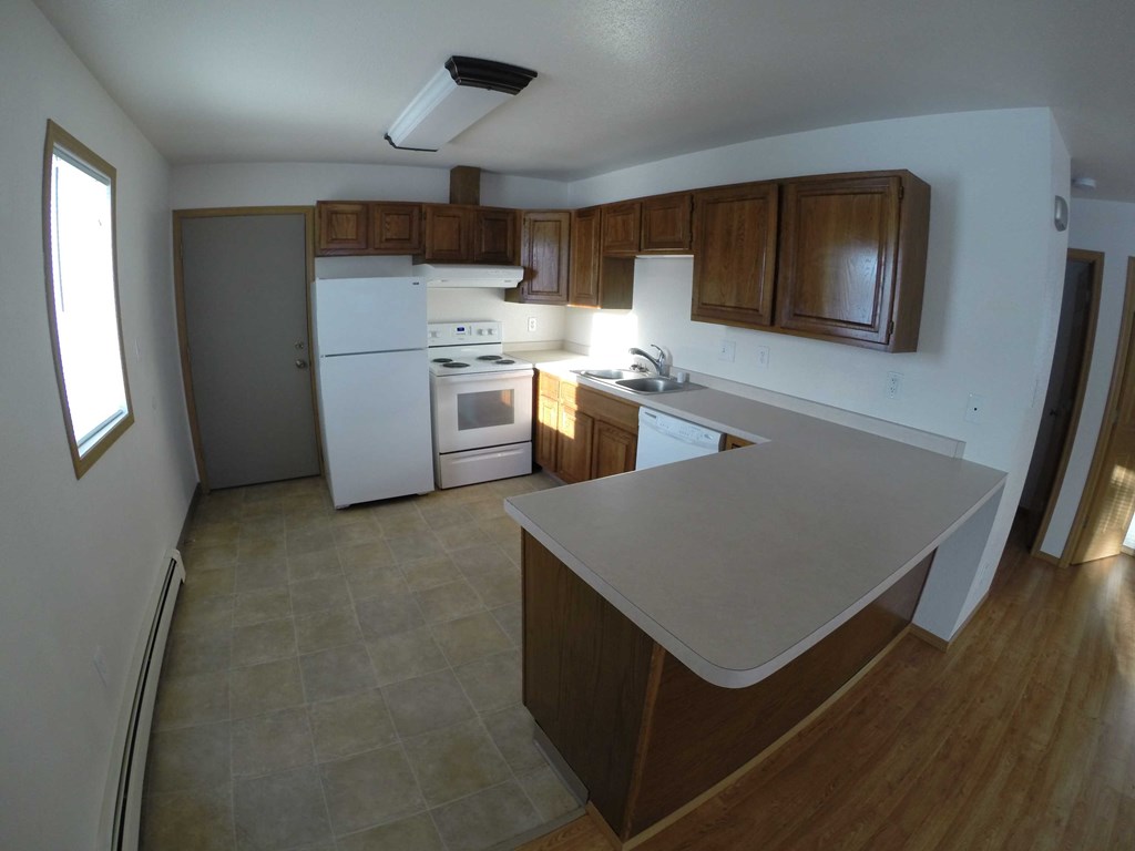 A kitchen with a white fridge, white oven, and wooden cabinets.