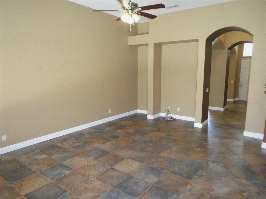 A room with a ceiling fan and tile flooring.