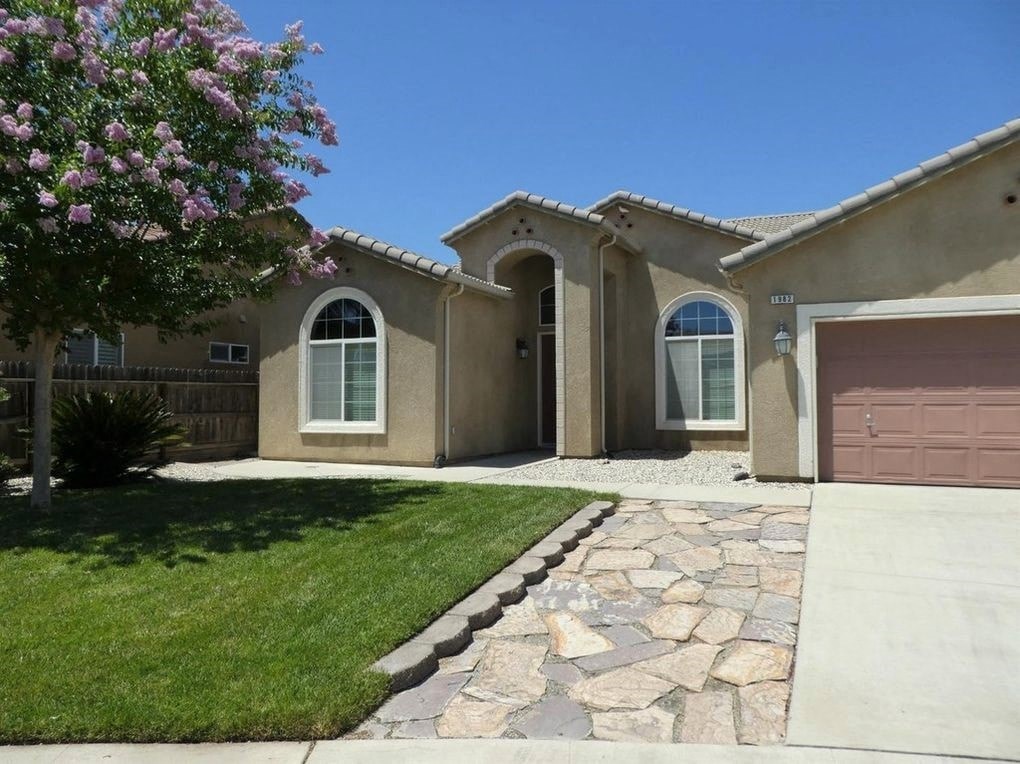 A house with a brown garage door and a stone pathway leading to it.
