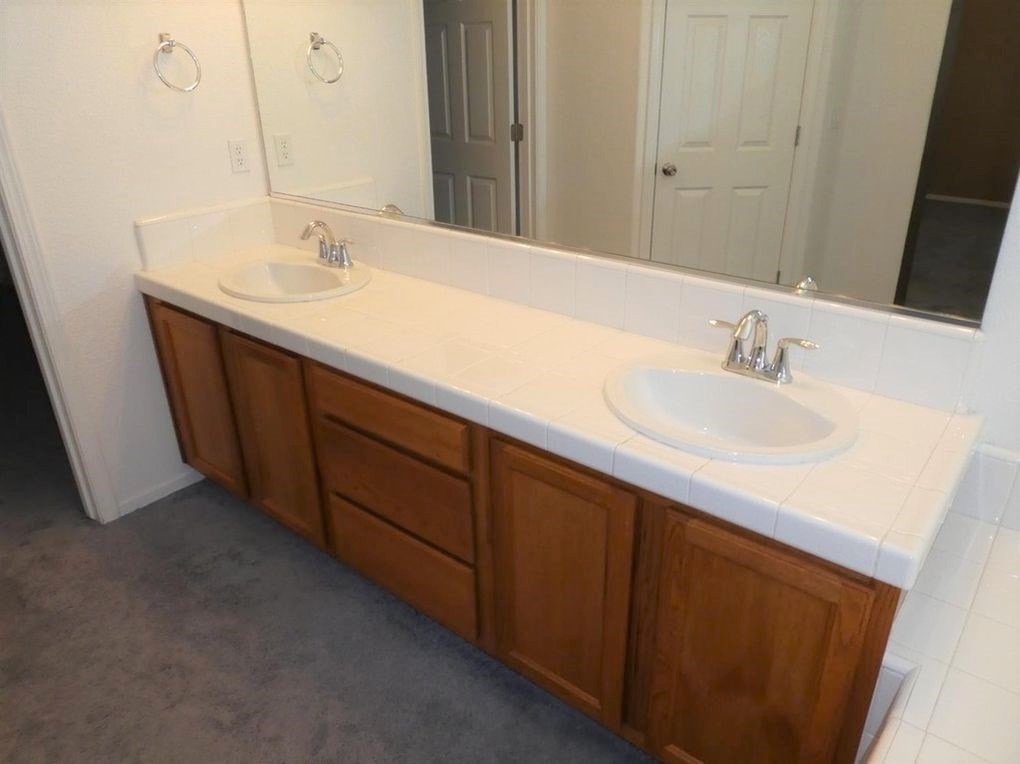 A bathroom with a white countertop and a white sink.