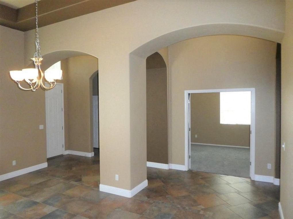 A room with a chandelier and arched doorways.