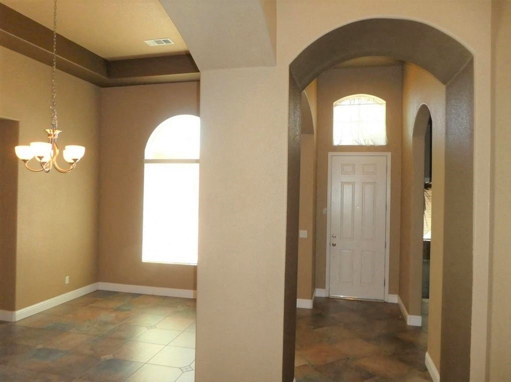 A hallway with a white door and a chandelier.