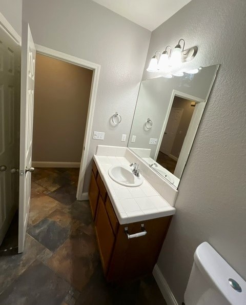 A bathroom with a sink, mirror, and toilet.