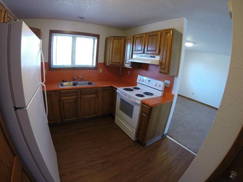 A kitchen with wooden cabinets and a white stove top oven.