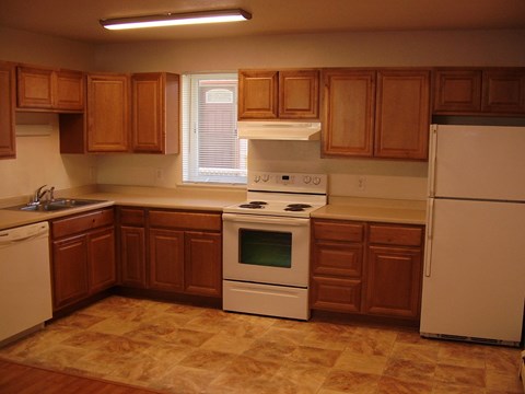 A kitchen with brown cabinets and white appliances.