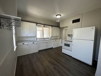 a kitchen with white appliances and white cabinets and wood floors