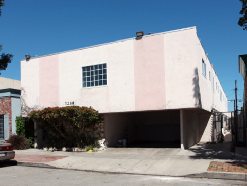 A white and pink building with a window and a garage door.