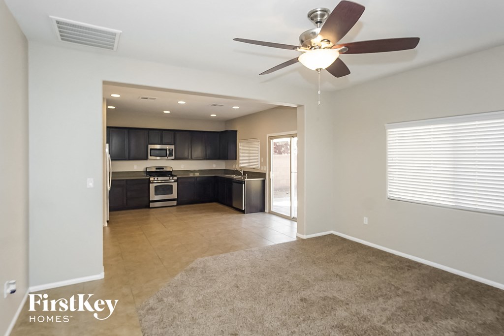 an empty living room and kitchen with a ceiling fan