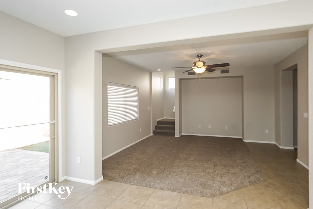 an empty living room with a ceiling fan and a door into a hallway