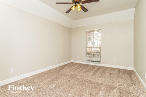 the spacious living room with carpet and a ceiling fan