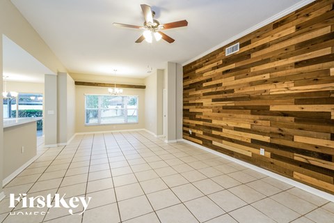 a dining room with a wood wall and a ceiling fan