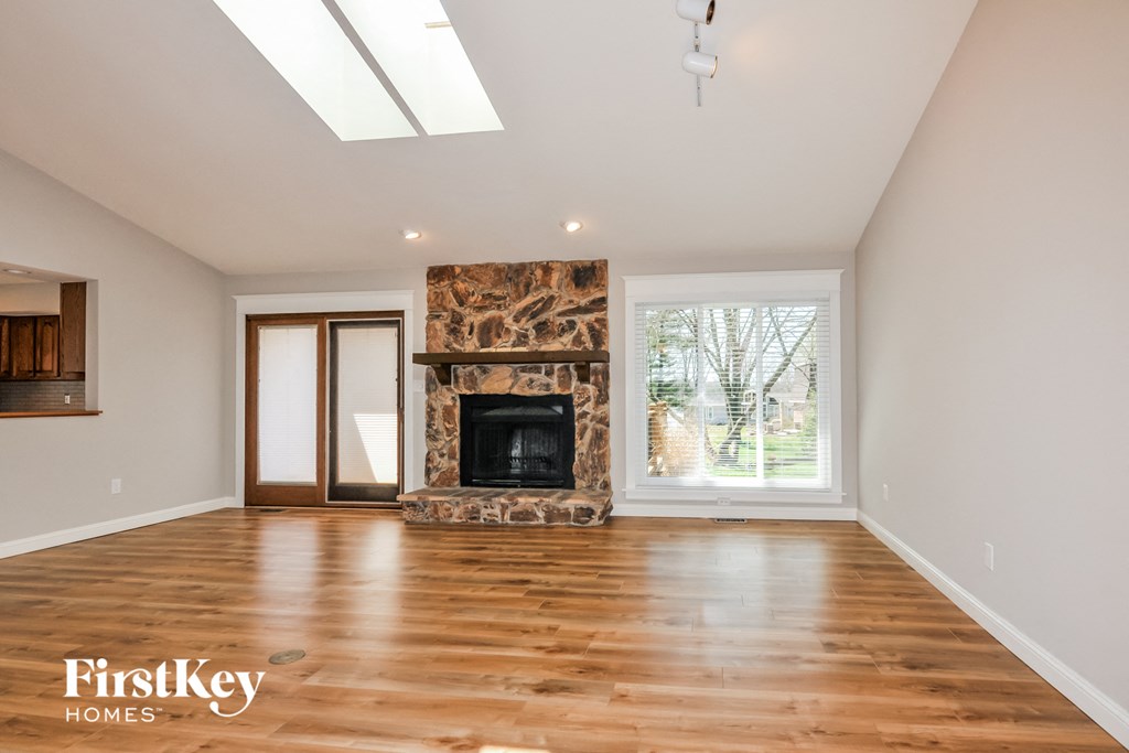 A spacious room with a fireplace and wooden flooring.