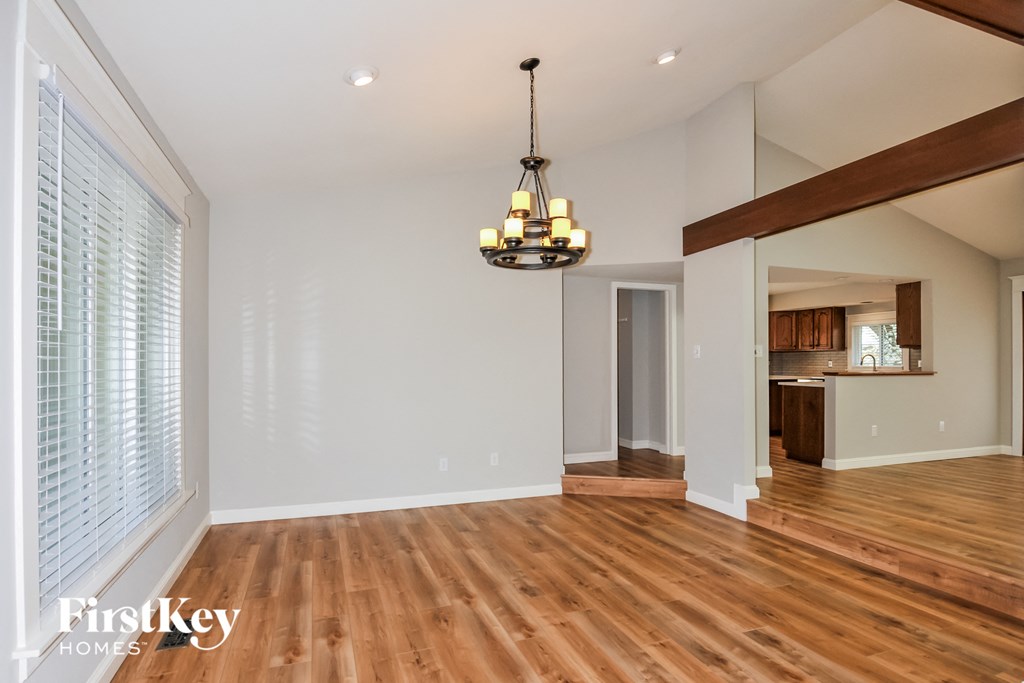 A large empty room with wooden floors and a chandelier hanging from the ceiling.