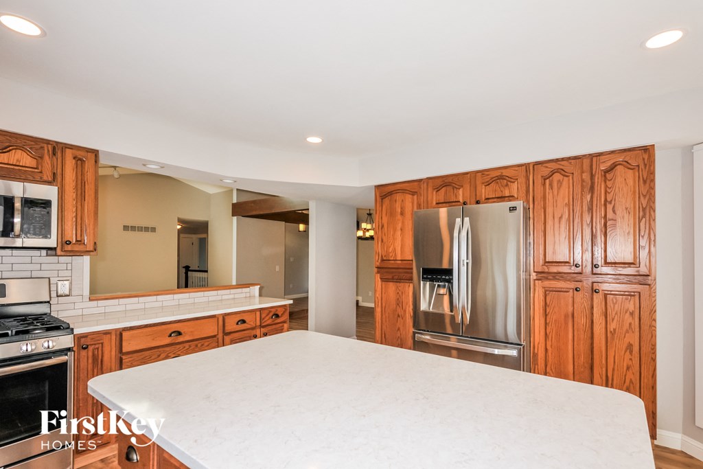 A kitchen with wooden cabinets and a stainless steel refrigerator.