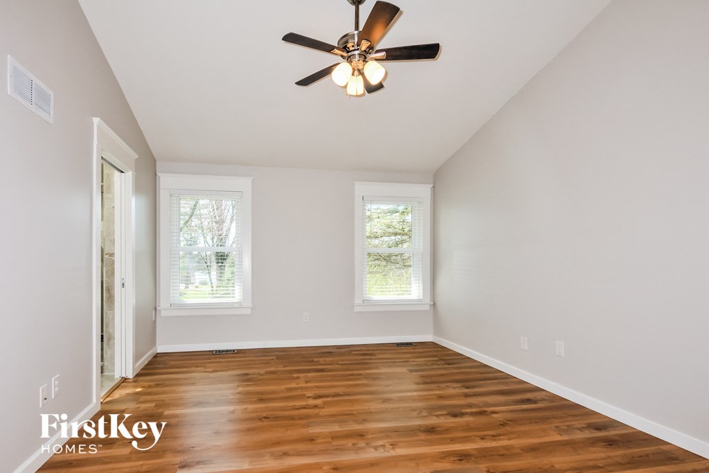 A room with a ceiling fan and wooden floors.