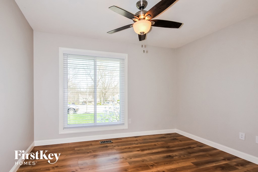 A room with a ceiling fan and a window with blinds.